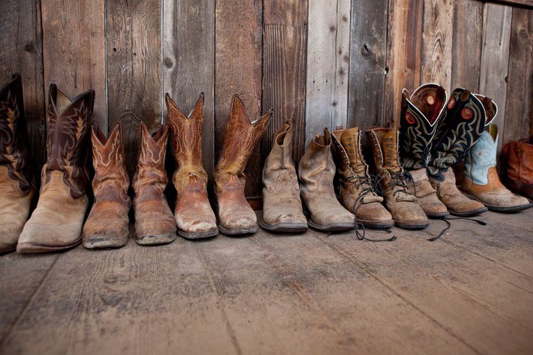 many pair of cowboy boots on the wood floor