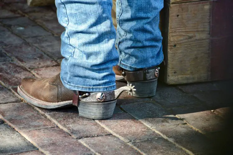 A man is stacking jeans with cowboy boots