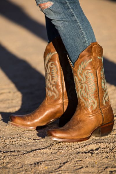 A woman wears ripped jeans with brown cowboy boots