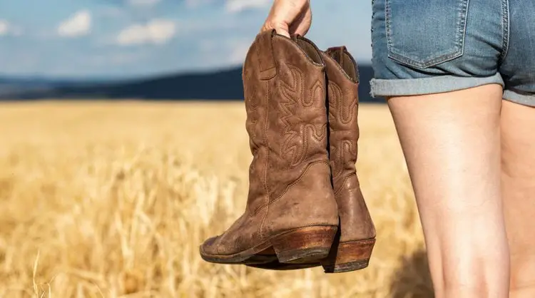 Girls carry a pair of cowboy boots on the field