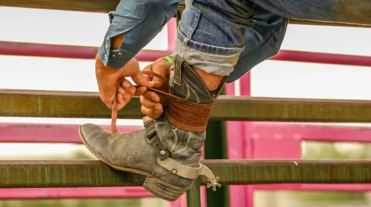 Man tightening his cowboy boot shaft with leather lace