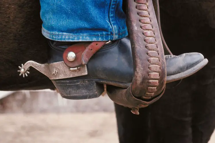 Man wear cowboy boots and are riding a horse