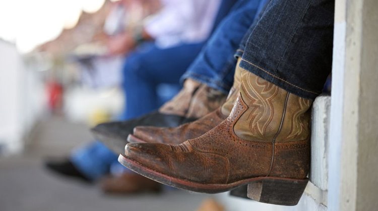 Man wear cowboy boots and jeans sitting down