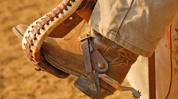 Man wear cowboy boots with tactical pants and riding a horse