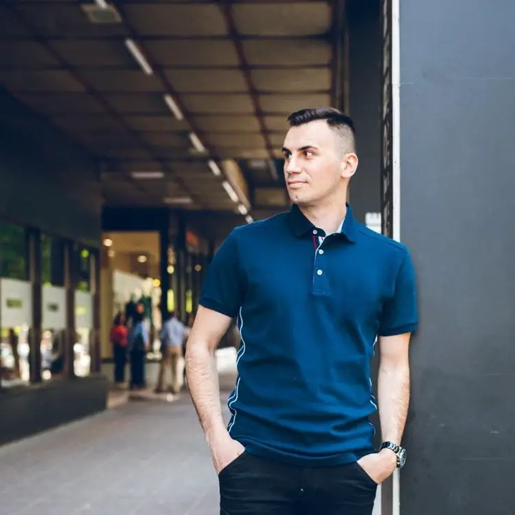 A man wears a blue polo shirt and black jeans