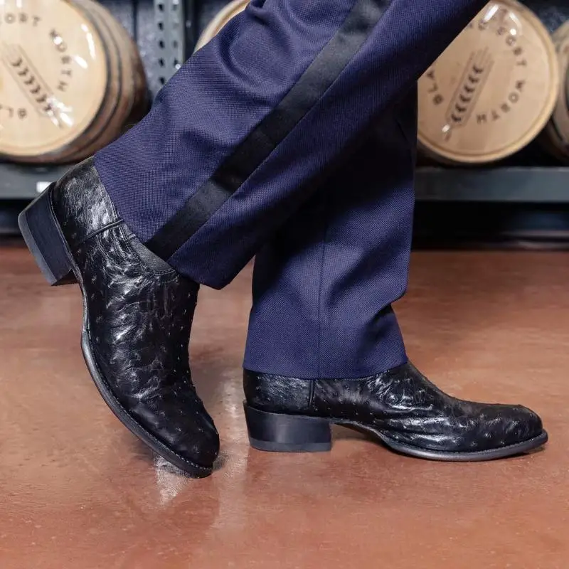 a man wears slacks and The Wyatt midnight ostrich boots from Tecovas