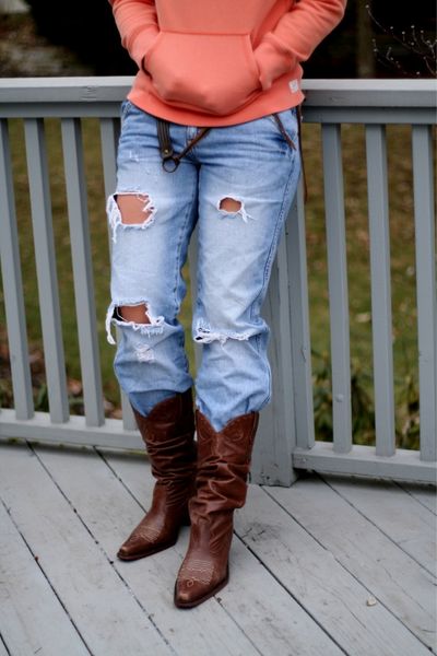 A woman wears Cowboy Boots with ripped jeans