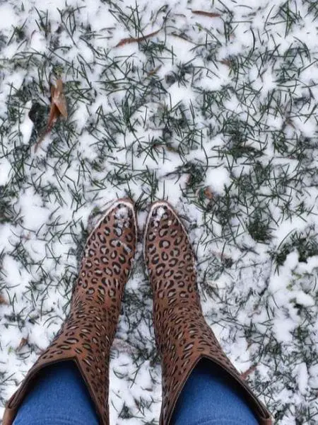 A woman wears cowboy boots and are standing on the snow