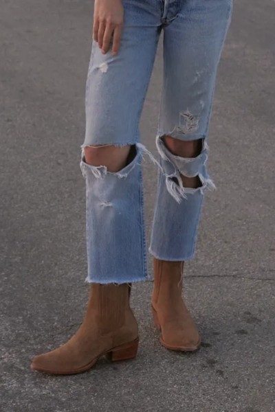 A woman wears ripped jeans with The Taylor cowboy boots from Tecovas