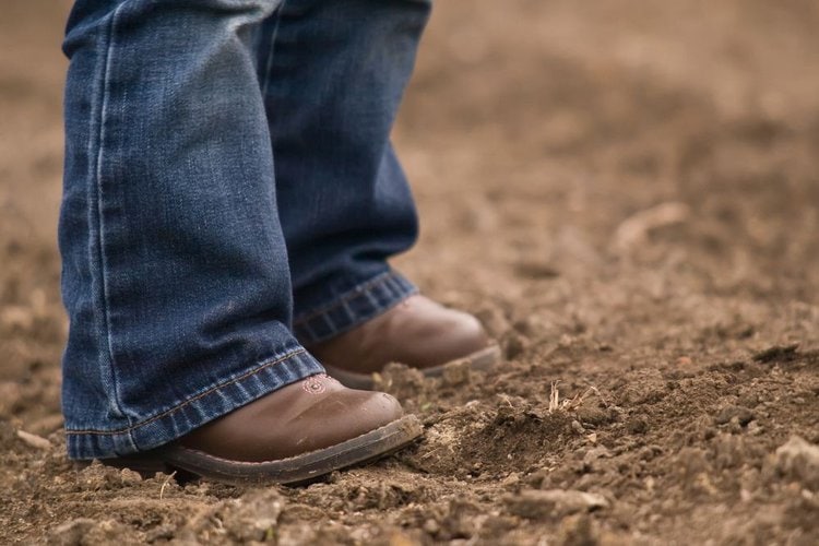 Man wear cowboy boots and stand on the muddy place