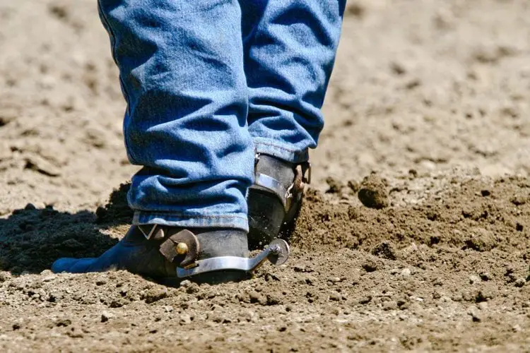 Man wears cowboy boots on the dirty mud ground on ranch