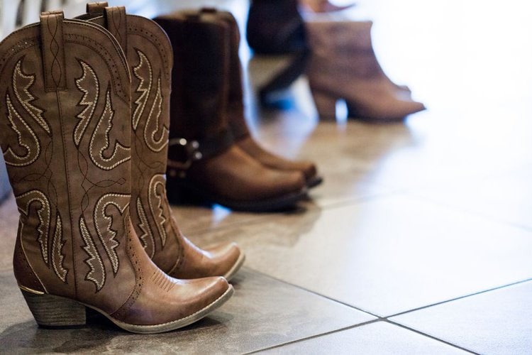 Many pairs of cowboy boots on the floor