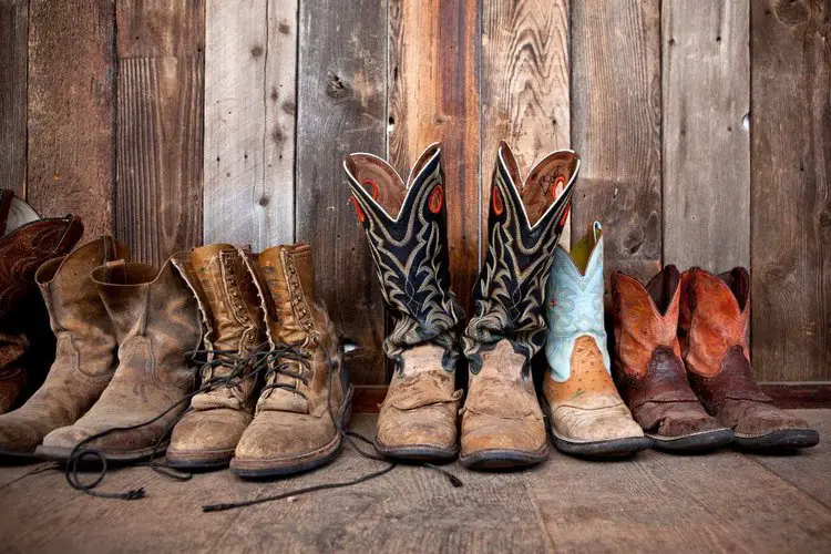 Many pairs of cowboy boots on the wooden floor