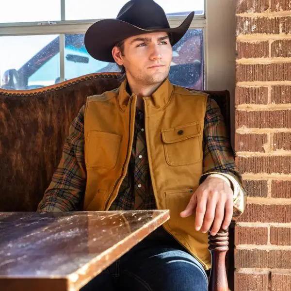 Man wear Canvas Vest with cowboy hat and sit in the mini bar