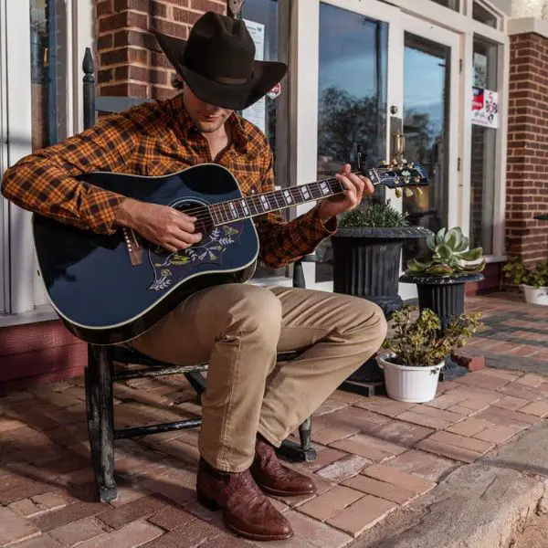 Man wear pearl snap shirt and playing a guitar