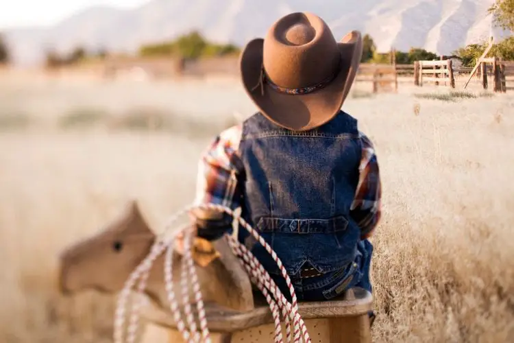 a boy wears a cowboy hat in the sun