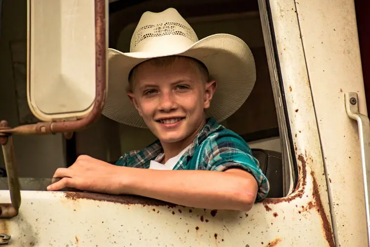 a boy wears his father cowboy hat