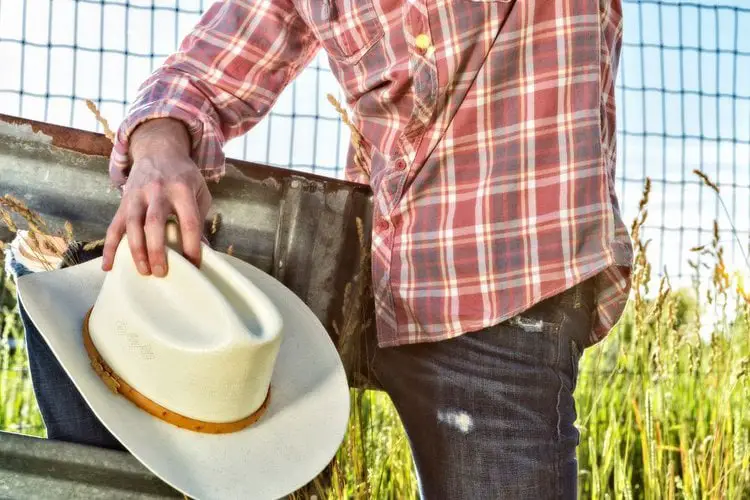 a man holds his cowboy hat