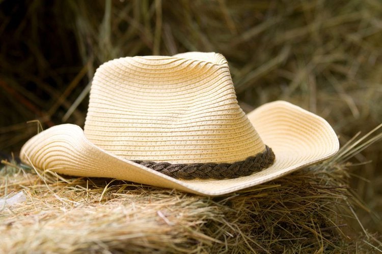 a straw cowboy hat on a pile of straw