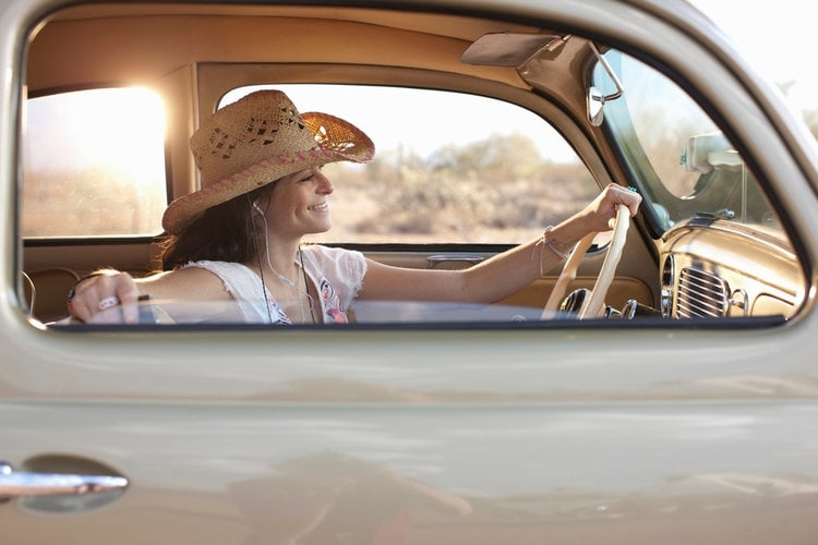 a woman enjoy driving a car while wearing cowboy hat