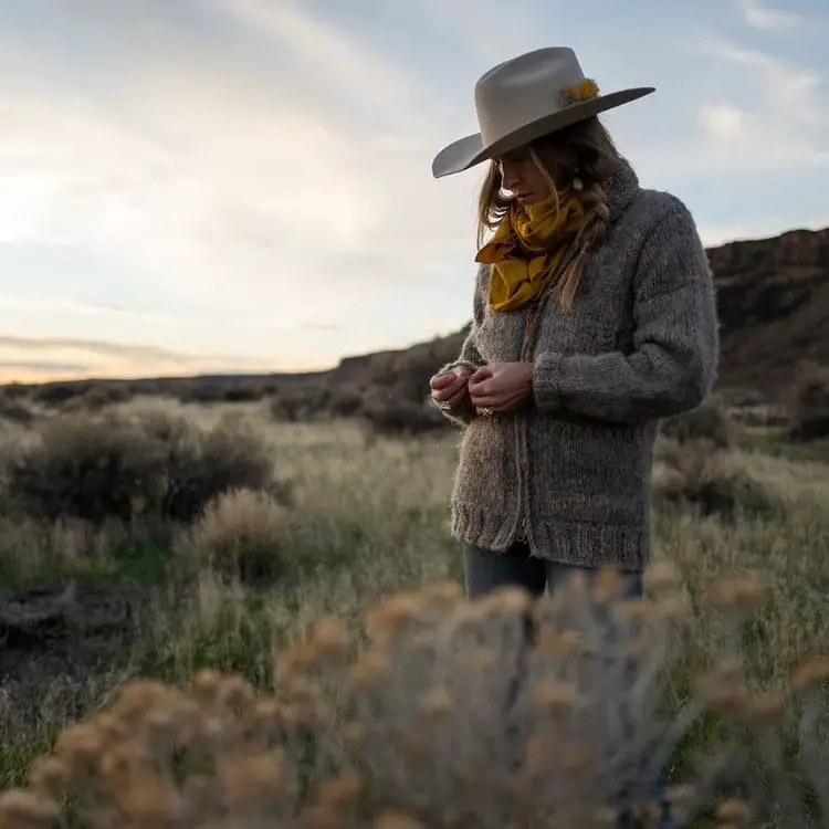 a woman wears The Ranchman cowboy hat from Tecovas and stands on the field