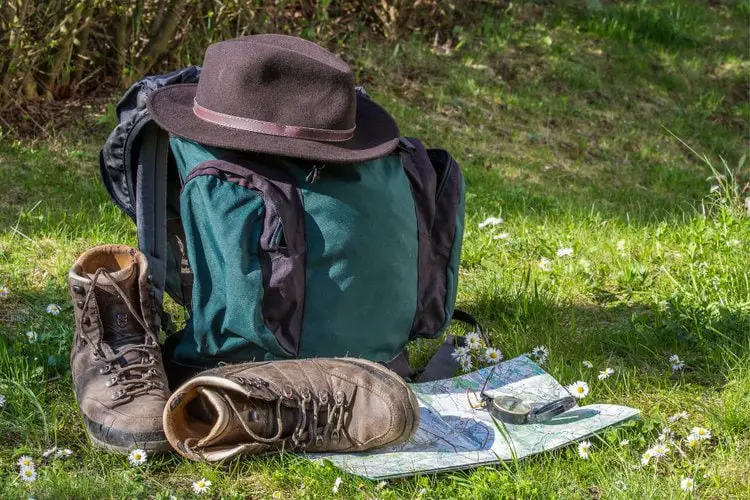 cowboy hat, backpack and hiking boots on the grass