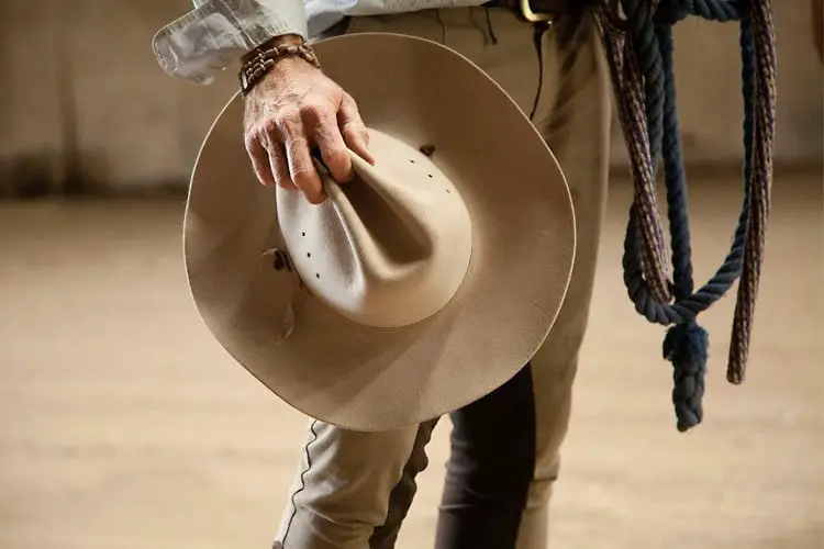 man holds a top of cowboy hat in his hand