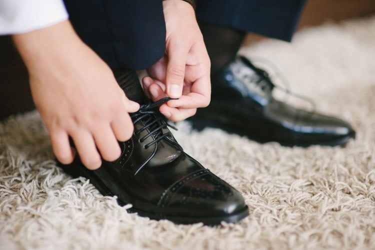 man is tying his dress shoes