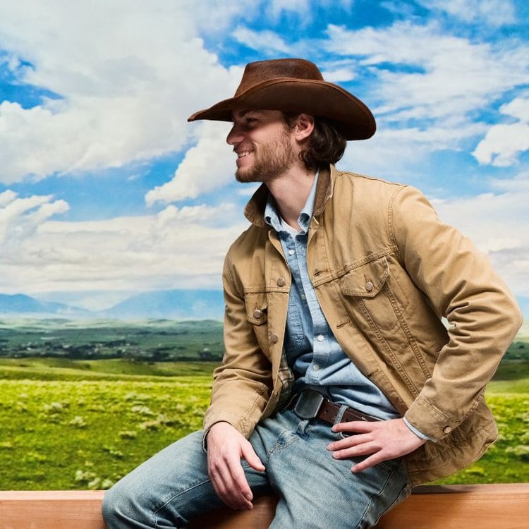 man is wearing felt cowboy hat, denim jacket and jeans under the hot sun