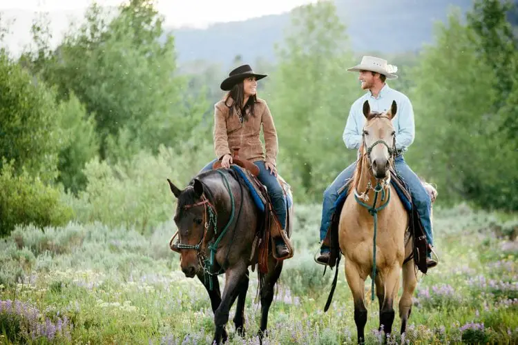 two ranchers wearing cowboy hats sit on the horsebacks