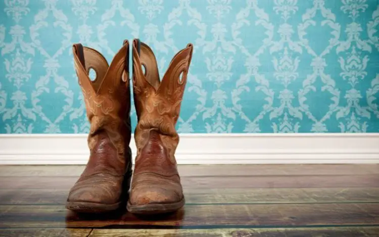 A pair of cowboy boots on the wooden floor.
