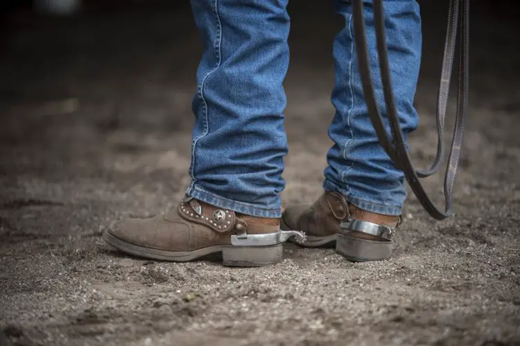 A man wears jeans with cowboy boots on the ranch.