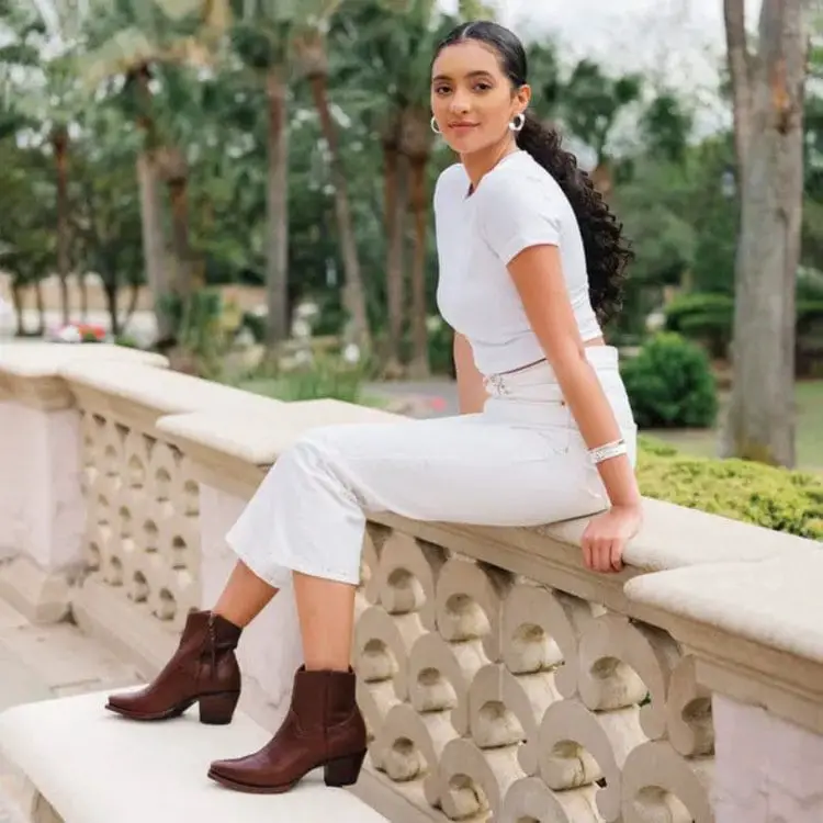 A girl wears The Penny western booties with white pants and shirt