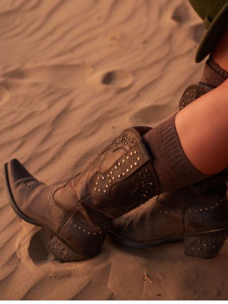 A woman wears socks with cowboy boots in the desert