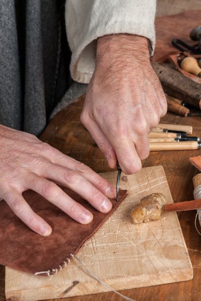 A cobbler is cutting leather