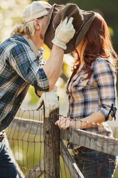 A man kiss a woman and cover it with a cowboy hat