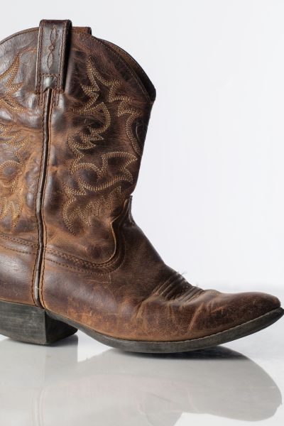 A pair of brown cowboy boots with a lot of black spot