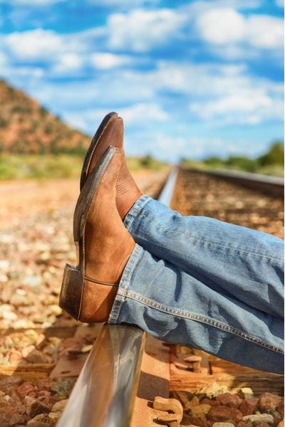 A man wears jeans with cowboy boots