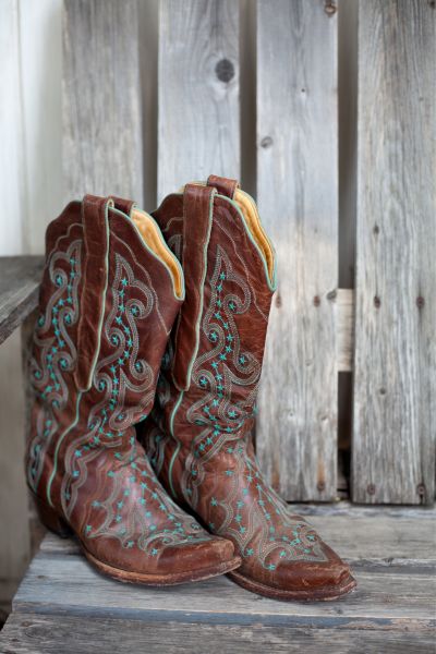 A pair of distressed leather cowboy boots on the wooden bench