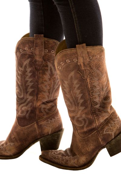 A woman wears distressed leather cowboy boots