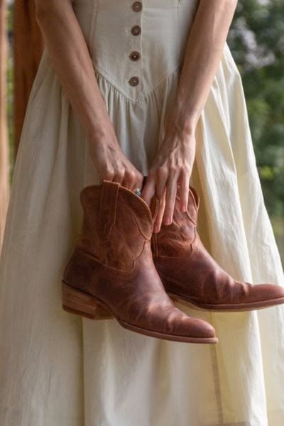 A woman wears dress with The Penny cowboy boots