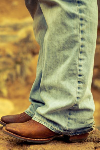 A man wears jeans with cowboy boots under the sun