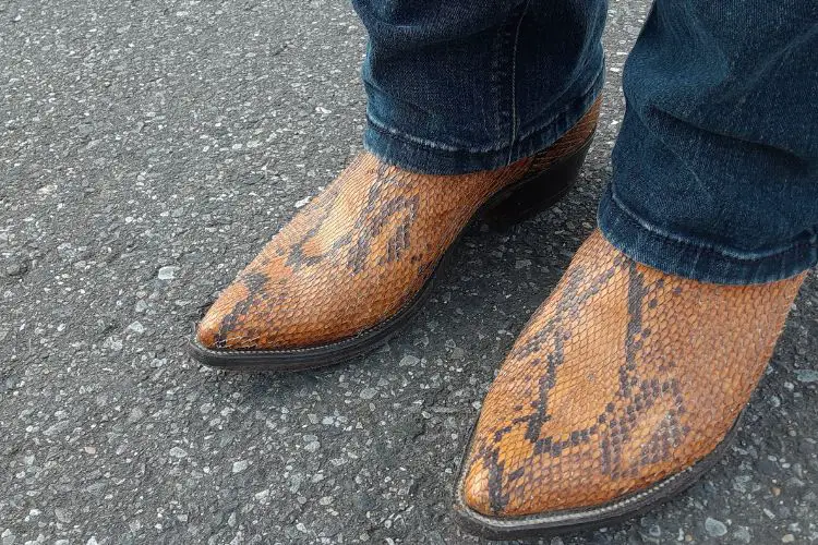 A man wears jeans with snakeskin cowboy boots