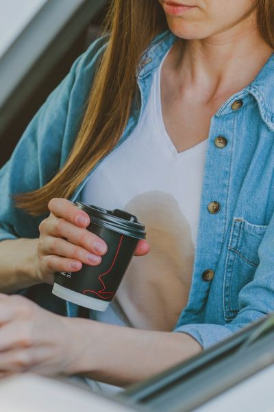 A woman falls the coffee on her denim shirt.