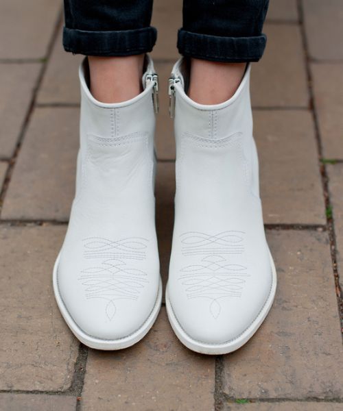 A woman wears black skinny jeans with white cowboy boots