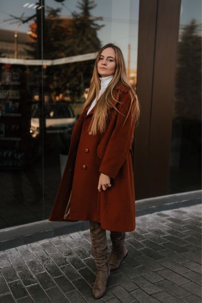 A woman wears over the knee boots with blazer