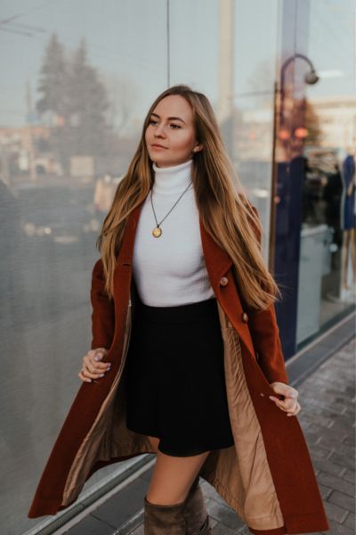 A woman wears over the knees boots with a mini skirt,a sweater and a blazer