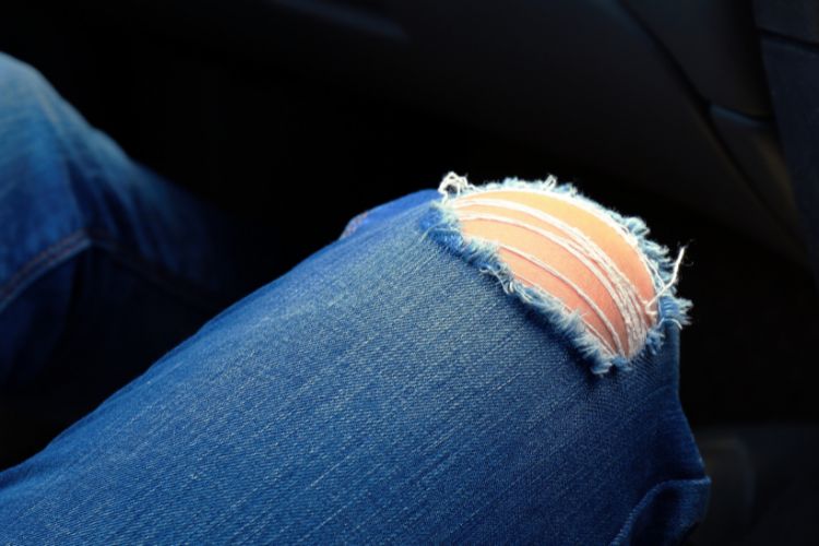 A woman wears ripped jeans at the knees