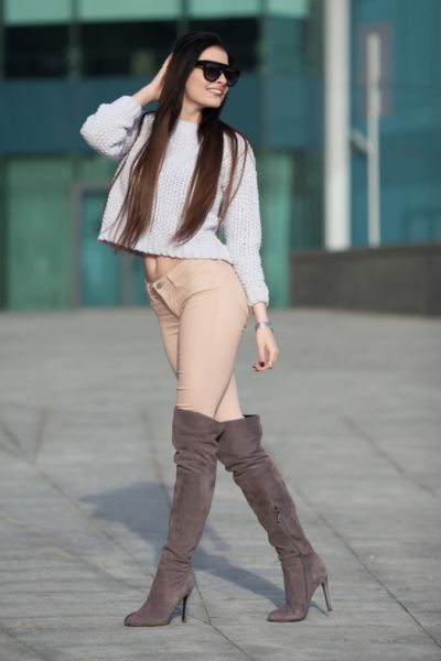 A women wears over the knee boots with leggings
