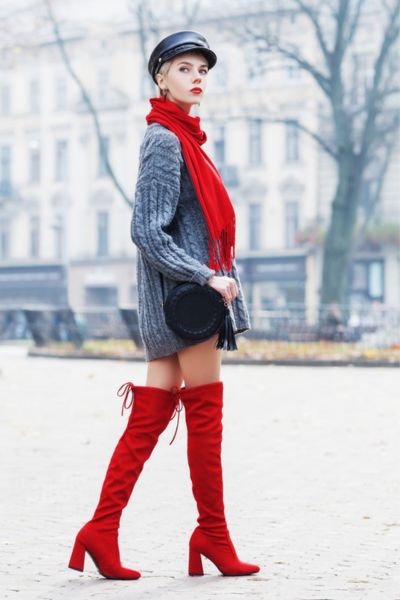 A women wears red over the knee cowboy boots and red beret